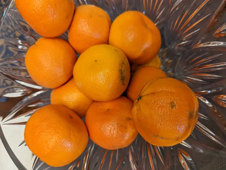 Small oranges piled in a cut-glass bowl, seen from above